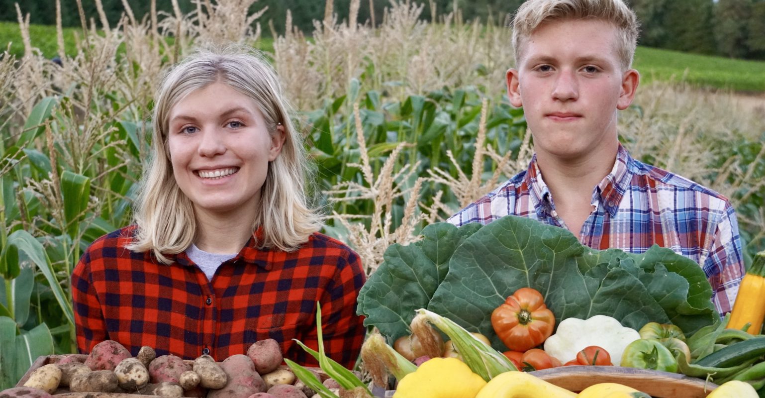 Kids behind baskets of produce.